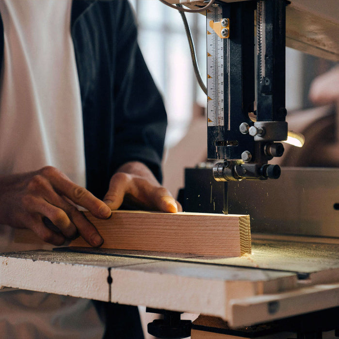 Mann sägt Holz auf Tischlereibandsäge